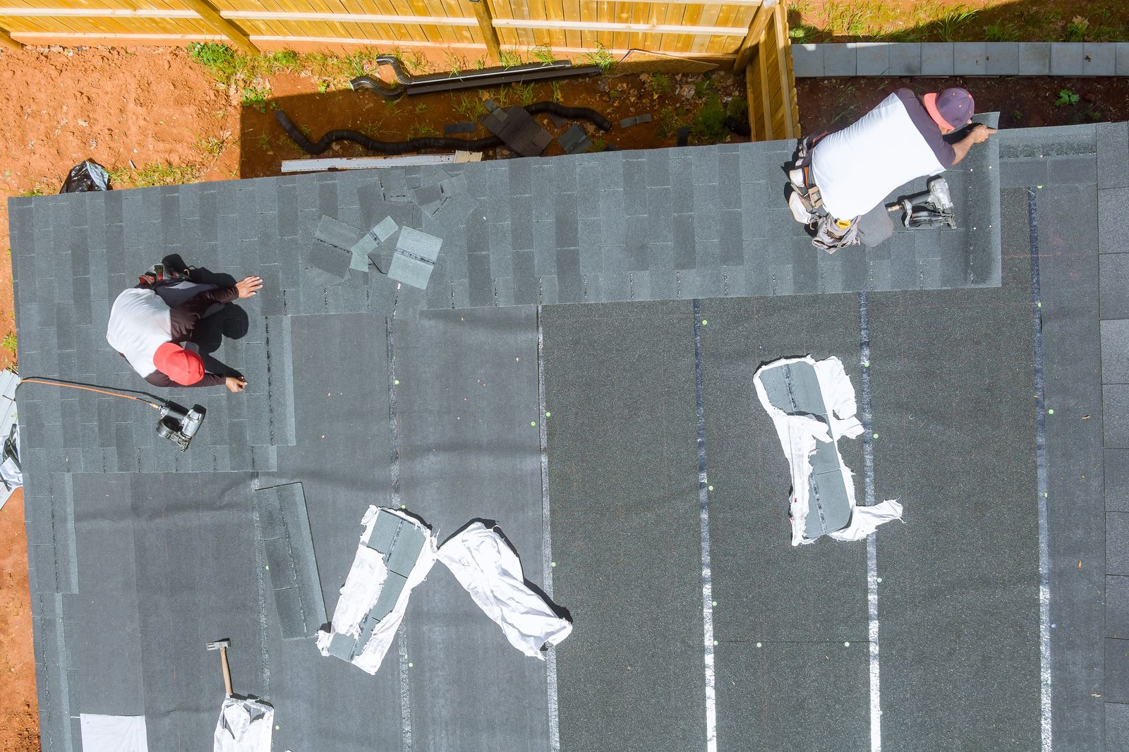 Aerial view of a roofing crew installing new asphalt shingles on a residential roof